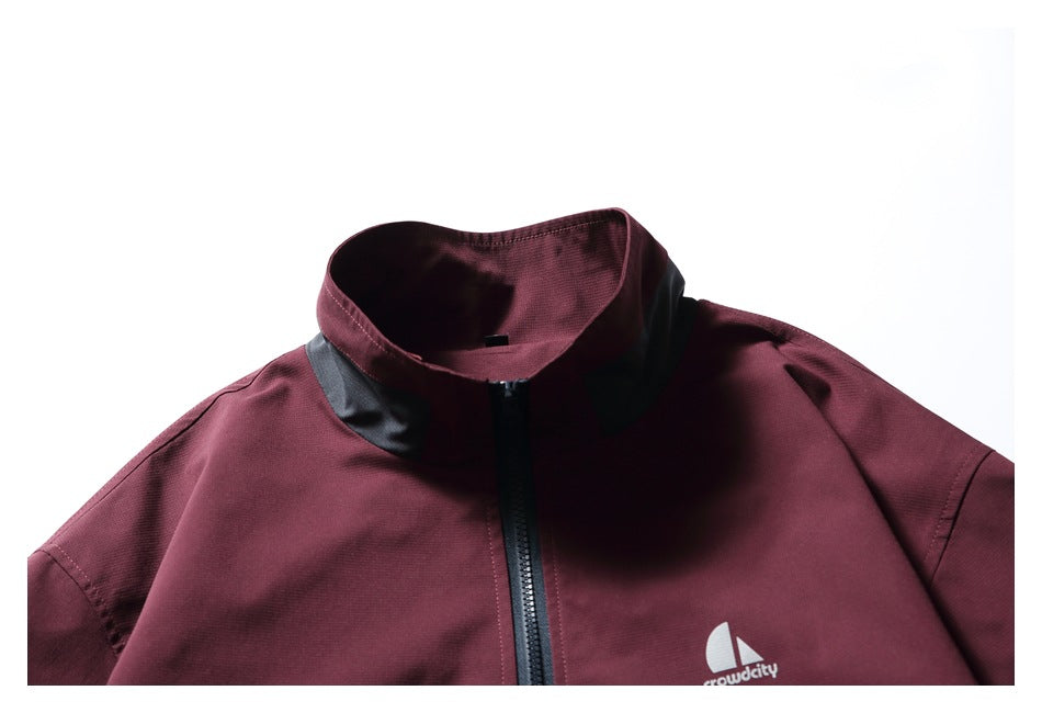 Close-up of a burgundy jacket collar, black trim and center zipper, with a small white chest logo.
