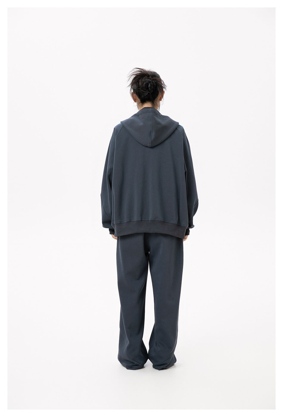 Back view of model wearing a dark gray hooded jacket with ribbed hem and matching wide-leg pants