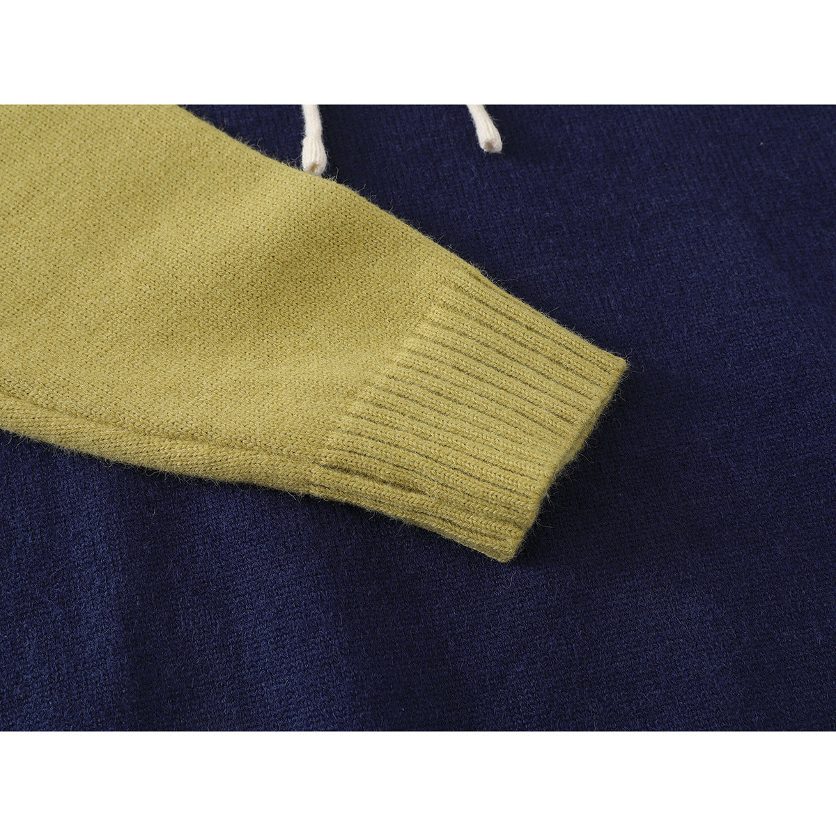 Close-up of a mustard-yellow knitted sleeve and ribbed cuff against navy fabric.