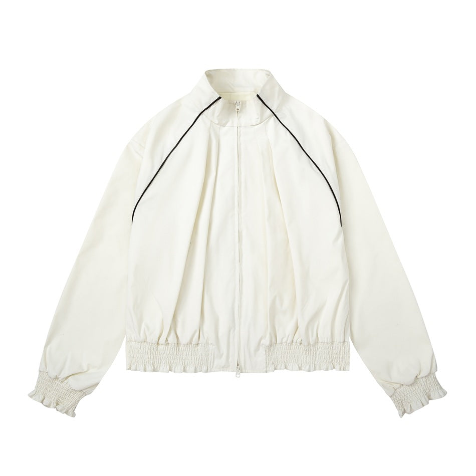 Off-white stand-collar zip jacket with black raglan piping and smocked ruffled hem and cuffs, flat lay front view