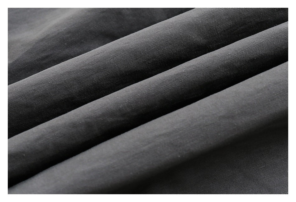 Close-up of dark charcoal fabric folded into diagonal ridges, showing its fine woven texture.