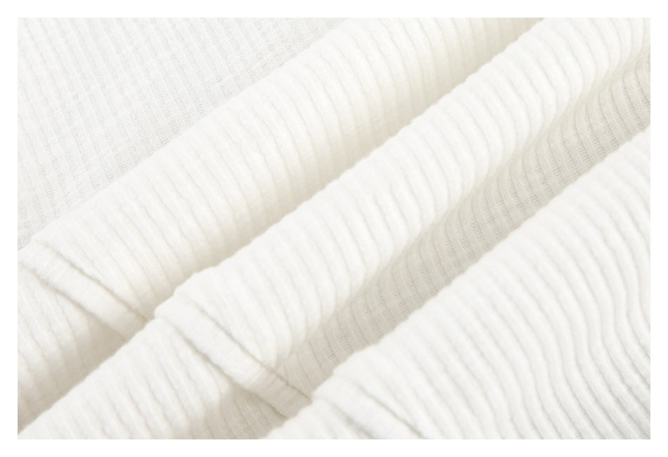 Close-up of folded ivory rib-knit fabric with prominent raised vertical ribs.