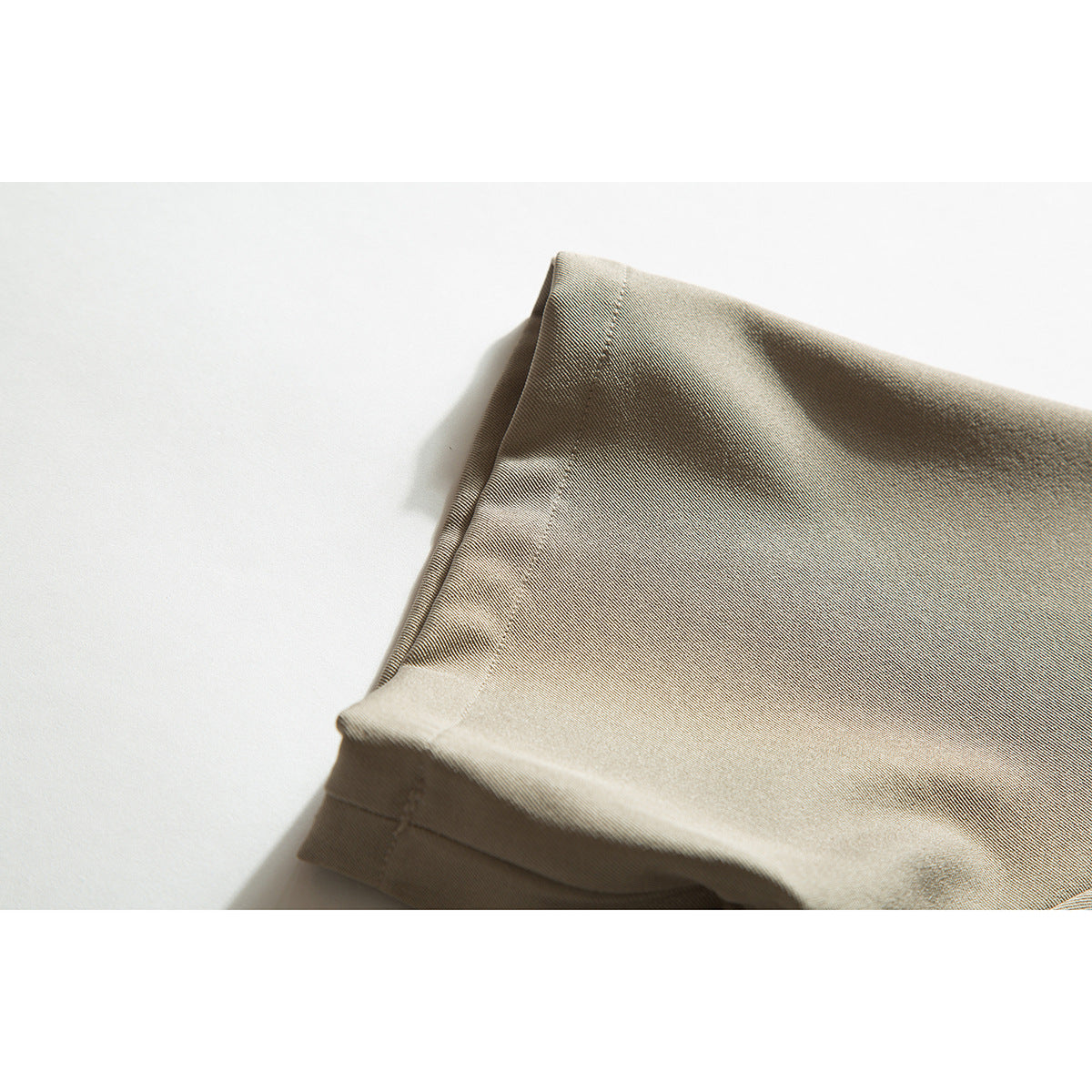 Close-up of the short sleeve cuff and stitching on a taupe shirt.
