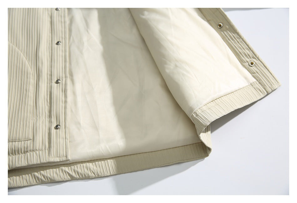 Inside view of an ivory pleated jacket showing smooth lining, snap fasteners, and a gathered hem.