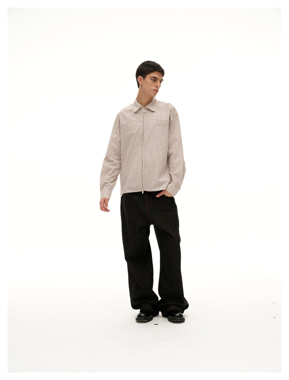Model wearing a red-and-white pinstriped zip-front shirt with wide black jeans, turned slightly to the side.