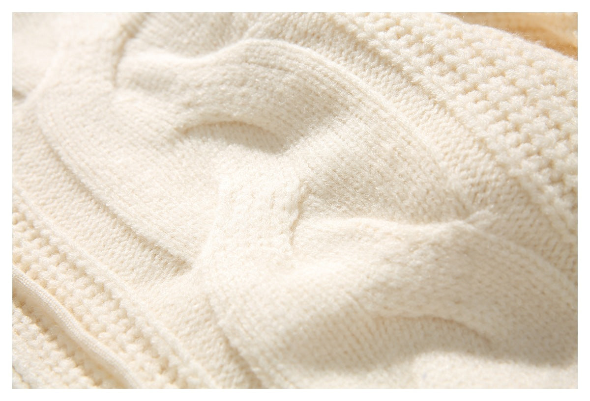Extreme close-up of the cream sweater's raised cable-knit pattern and textured stitches.