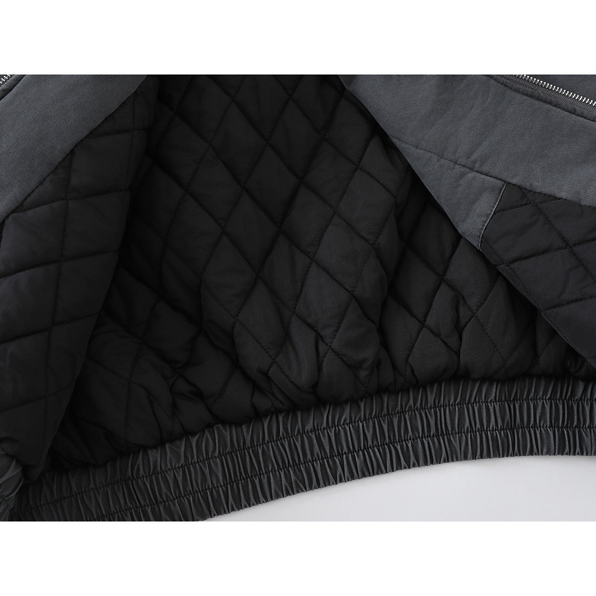 Close-up of a jacket opened to show its black diamond-quilted lining and gathered hem.