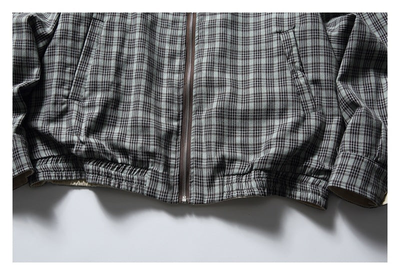 Close-up of the gray plaid jacket's front zipper, slanted pockets, and gathered hem.