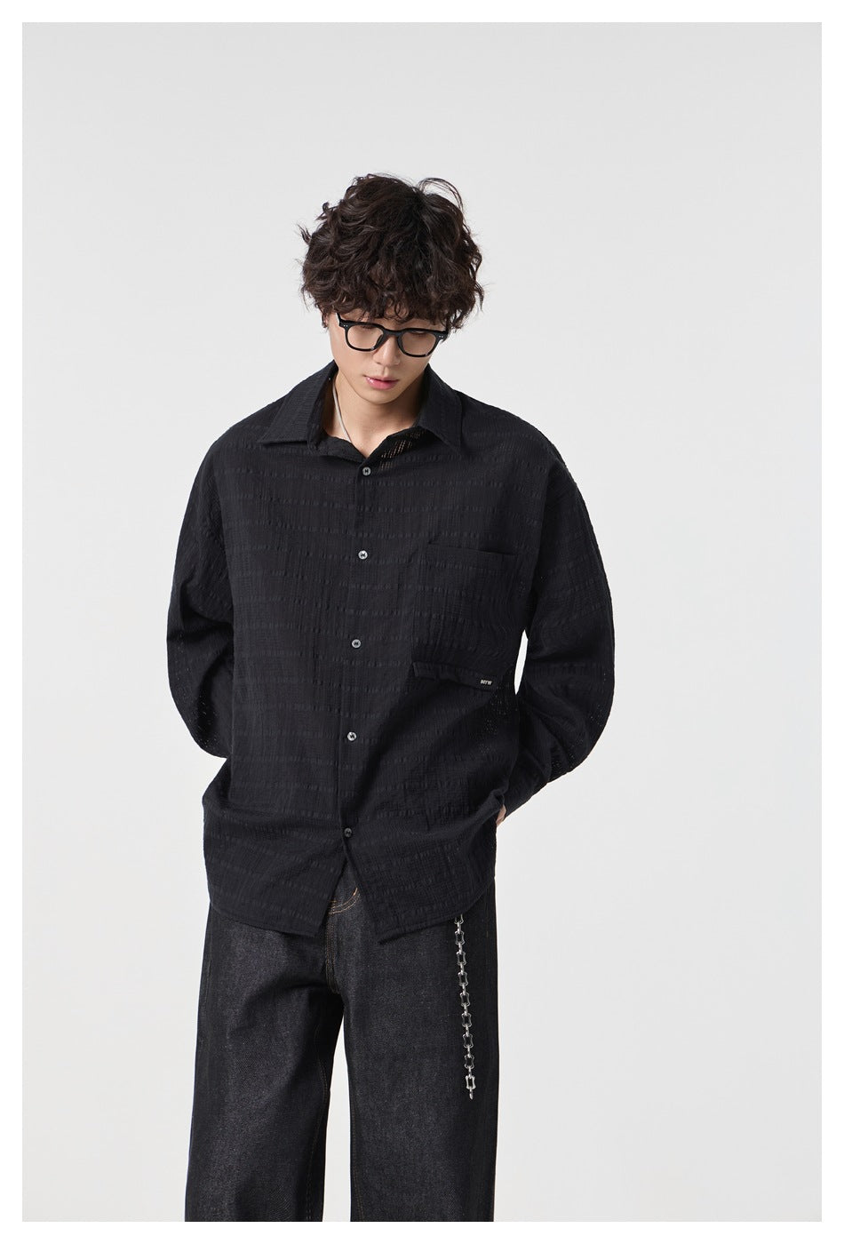 Closer view of a model wearing a black textured button-up shirt with a chest pocket.