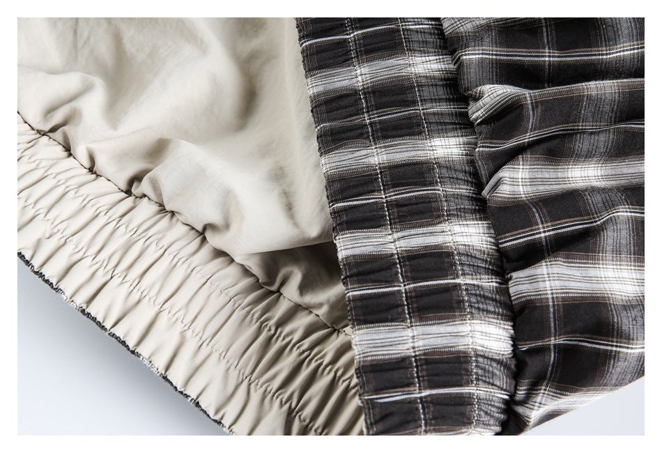 Close-up showing the light-colored inner lining and gathered elastic hem of the plaid jacket.