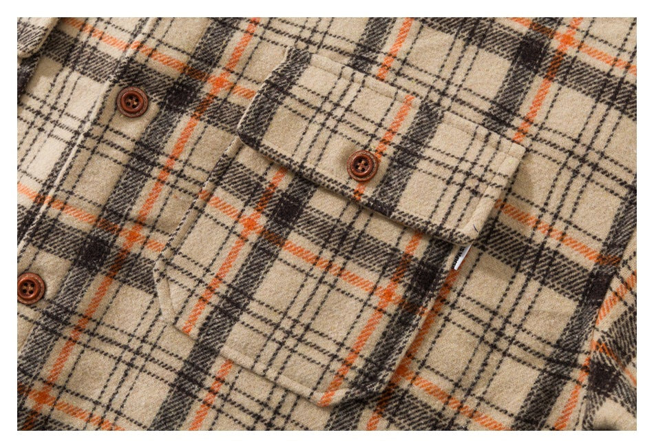 Close-up of a beige plaid shirt with orange and dark lines, buttoned chest pockets, and brown buttons.