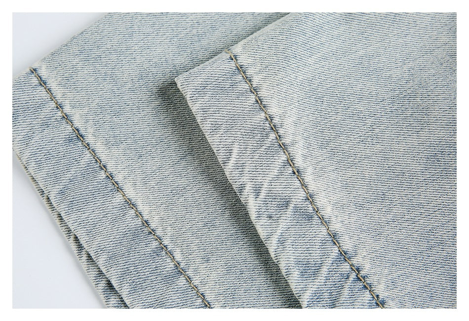 Close-up of folded denim fabric with parallel stitched edges and pale washed finish.