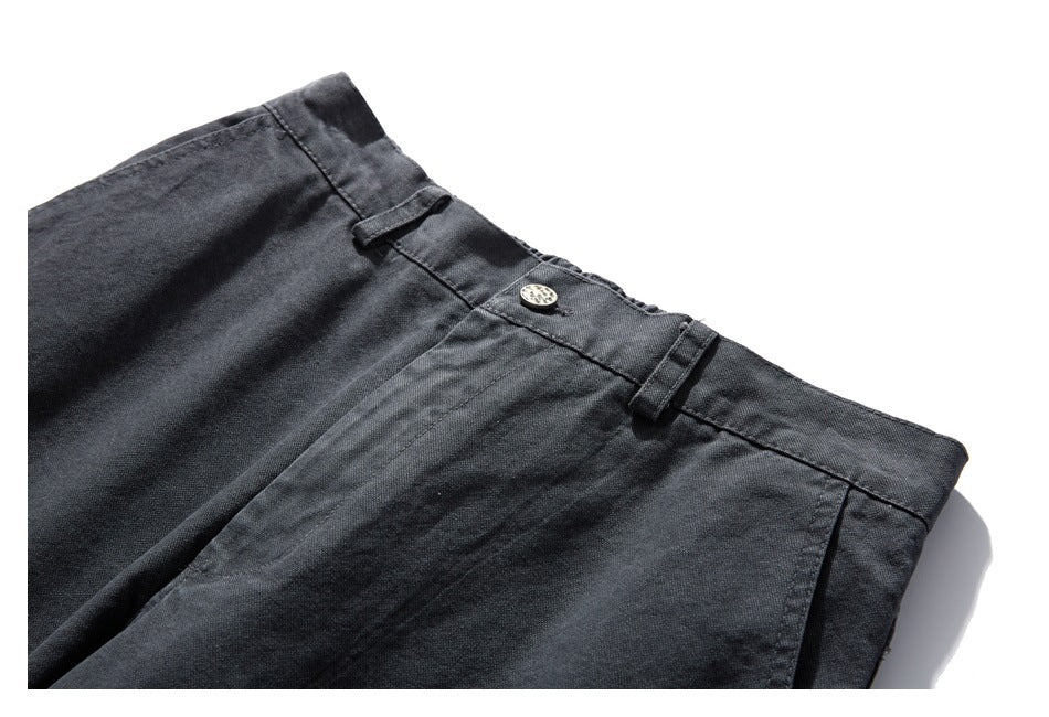 Close-up of the charcoal-gray trouser waistband, button, belt loops, and front pleats.
