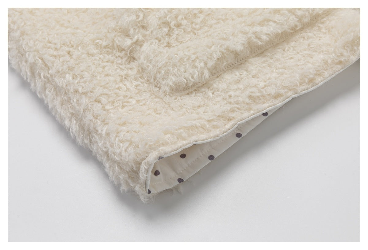 Close-up of the cream curly-pile garment hem, showing its white dotted lining.