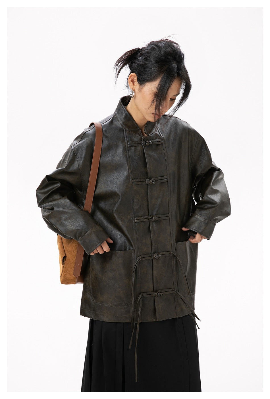 Model wearing an oversized dark brown jacket with frog closures, large pockets and a black skirt.