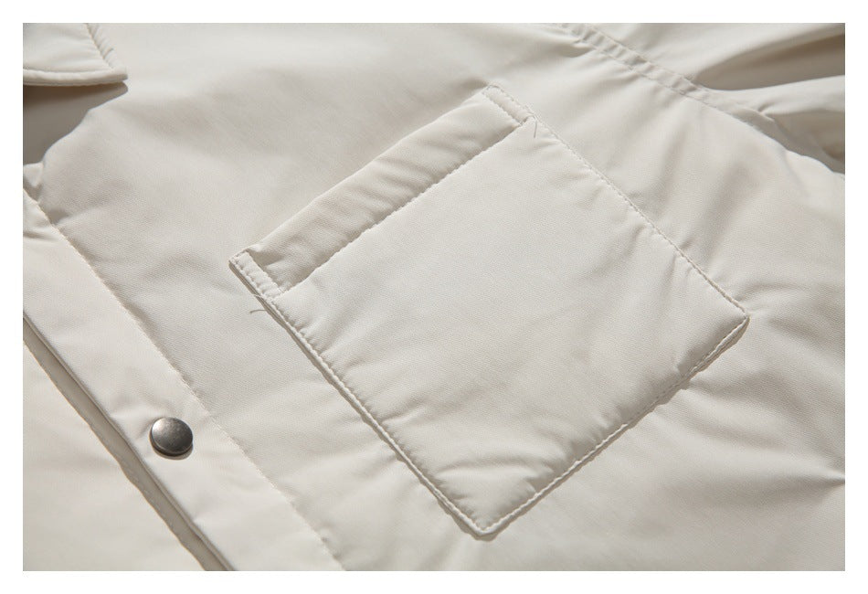 Close-up of the ivory jacket’s large stitched chest pocket and a metal snap on the placket.