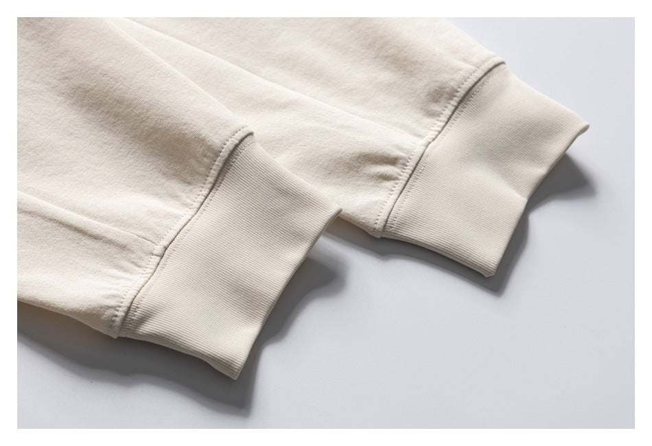 Close-up of two cream sweatshirt sleeves with wide ribbed cuffs.