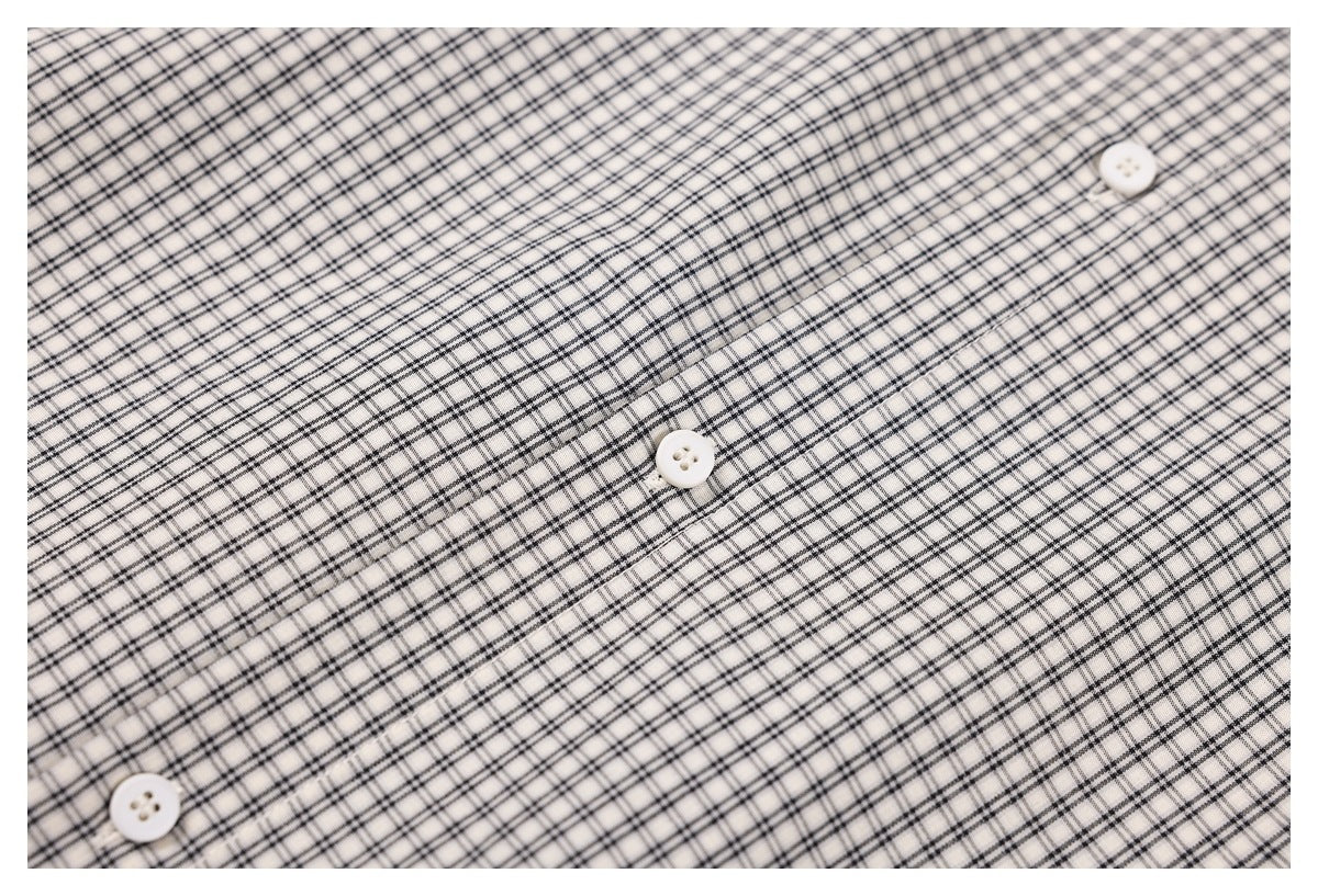 Close-up of black check fabric and three white buttons along the shirt's front placket.