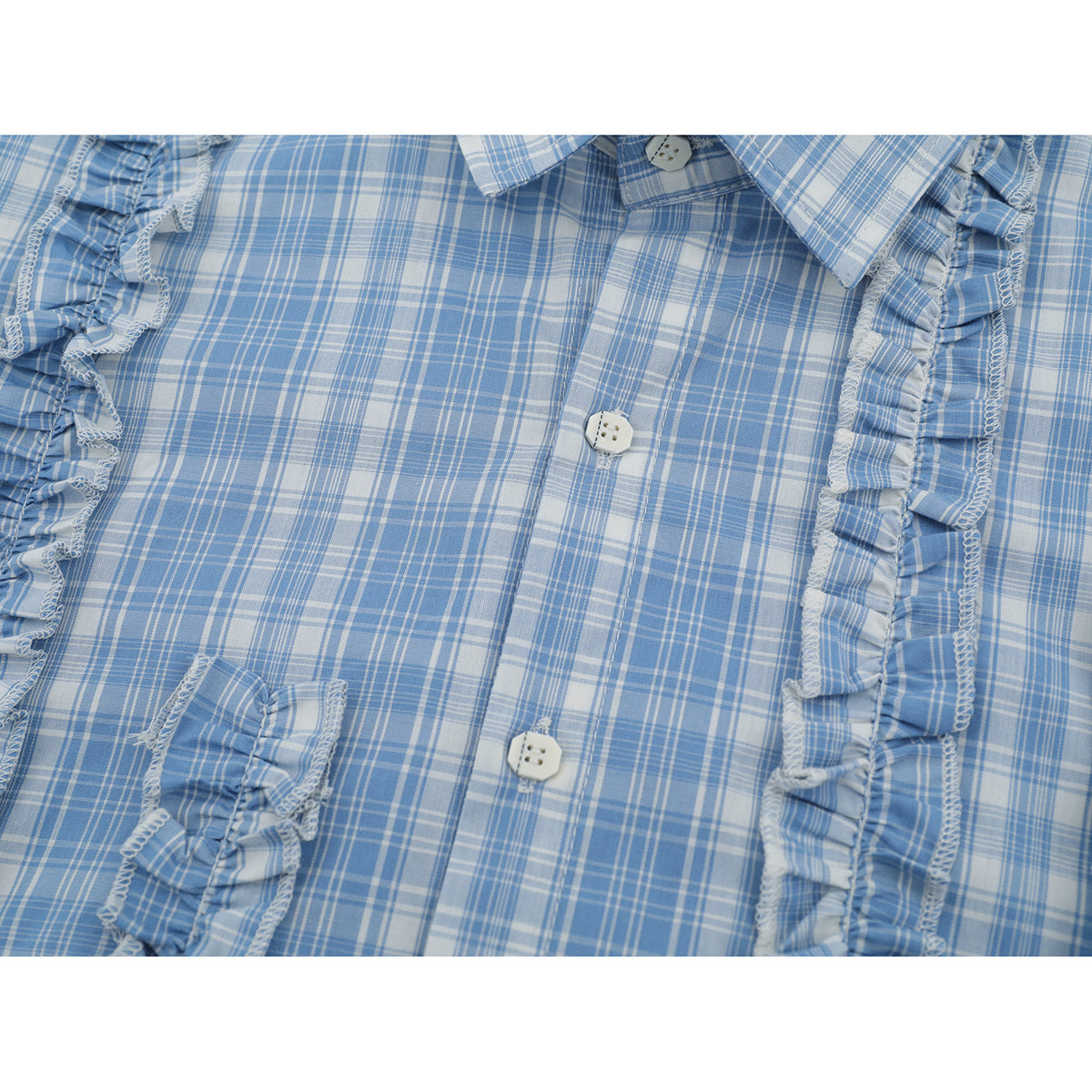 Close-up of a light blue and white plaid shirt front with a button placket and vertical ruffle trim.