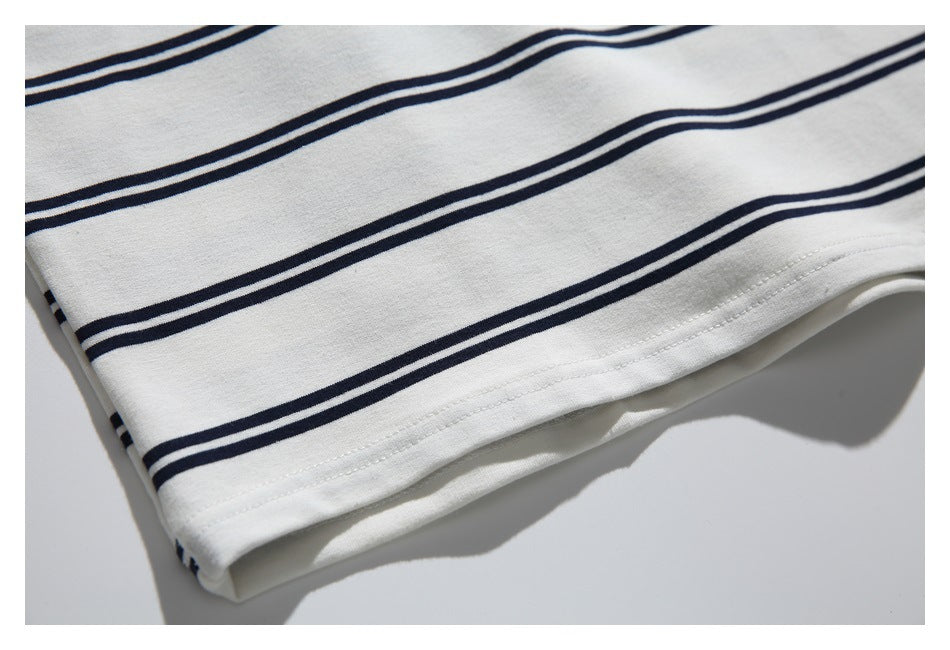 Close-up of the off-white fabric, paired navy stripes, and double-stitched bottom hem.