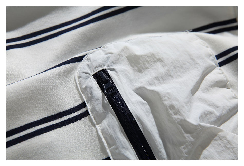 Close-up of a dark zipper on a white pocket over white fabric with navy stripes.