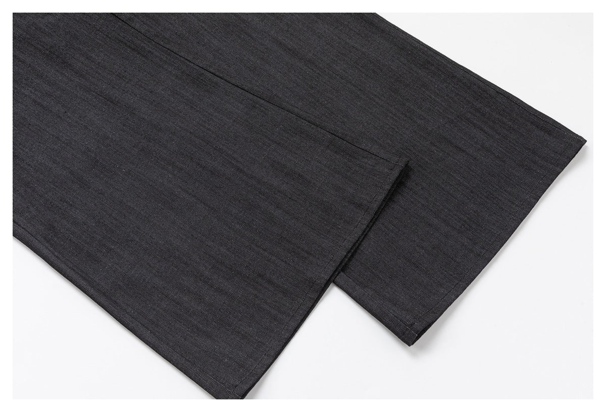 Close-up of a dark charcoal garment showing overlapping fabric panels and stitched edges.