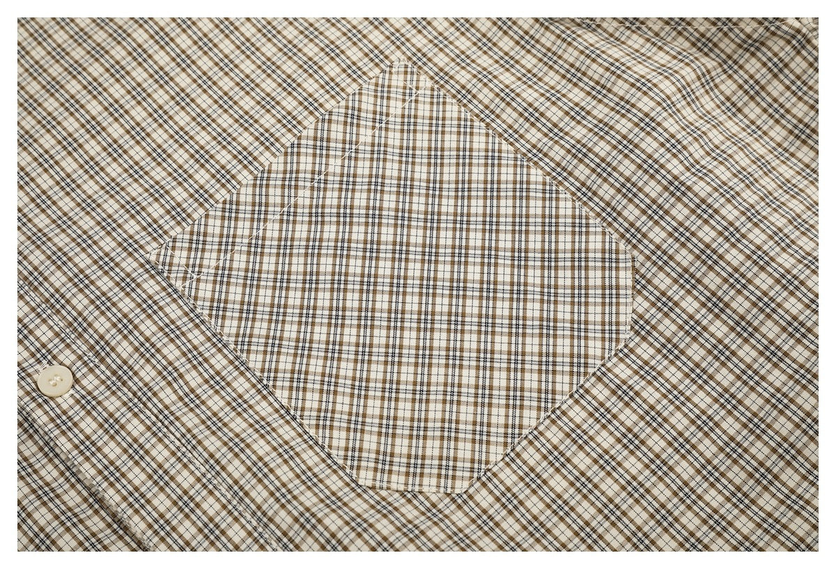 Close-up of a checked shirt's large patch pocket, showing the beige, brown, and black plaid pattern.