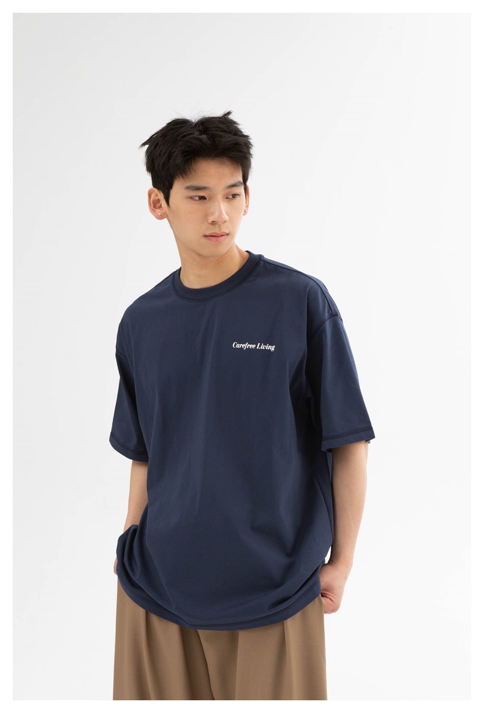 Three-quarter front view showing the navy T-shirt's short sleeves, relaxed fit, and small white chest print.