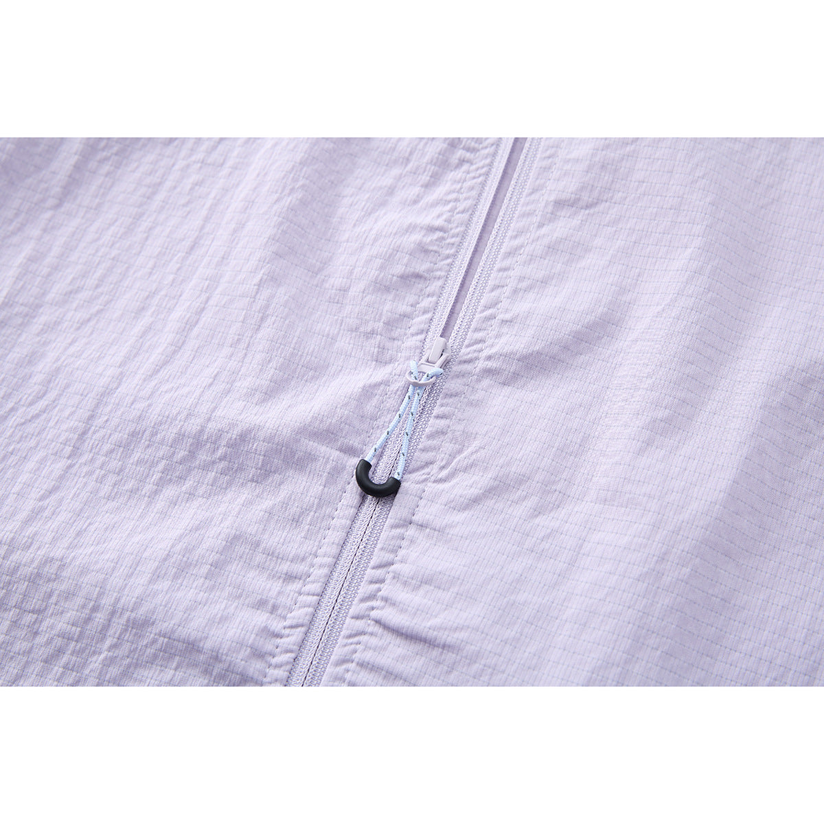 Close-up of a pale lavender jacket zipper with a cord pull and black hook-shaped end.