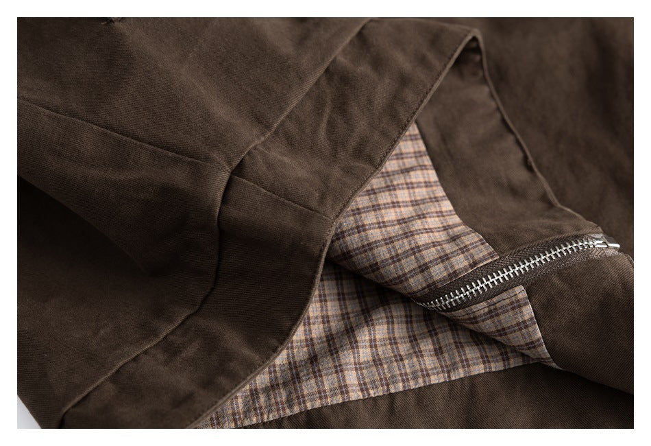Close-up of a dark brown jacket opening, showing a beige plaid lining and silver zipper.