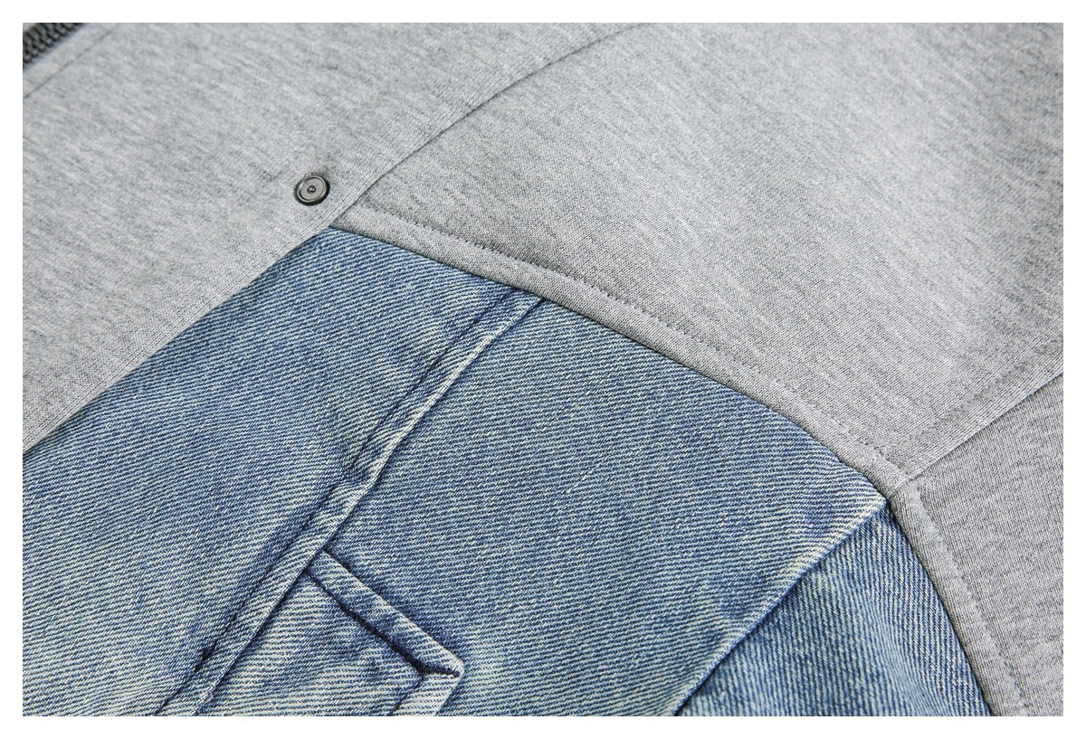 Close-up of gray and blue denim-like fabric panels with seam stitching and a small snap.
