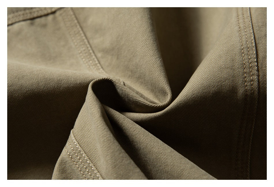 Close-up of olive-khaki garment fabric folds with visible stitching and seams.