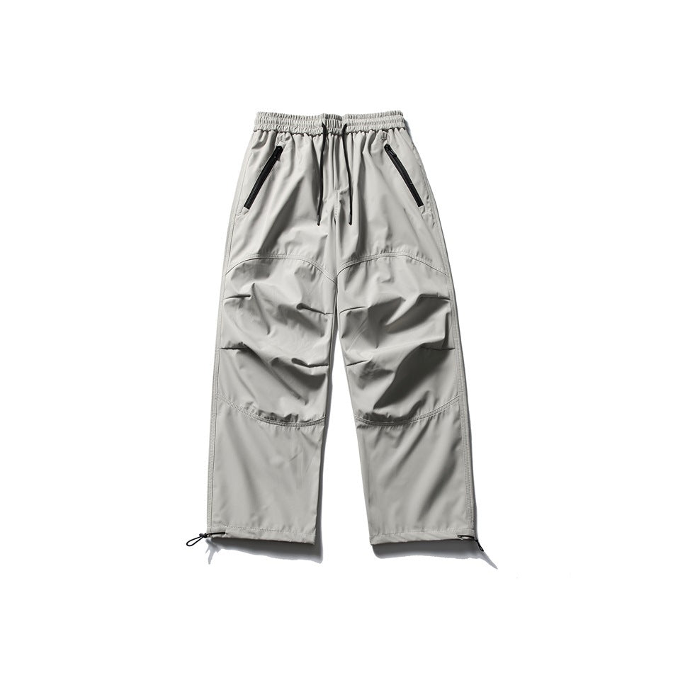 Light gray loose-fit cargo pants shown from the front, with an elastic drawstring waist, zip pockets, and adjustable cuffs.