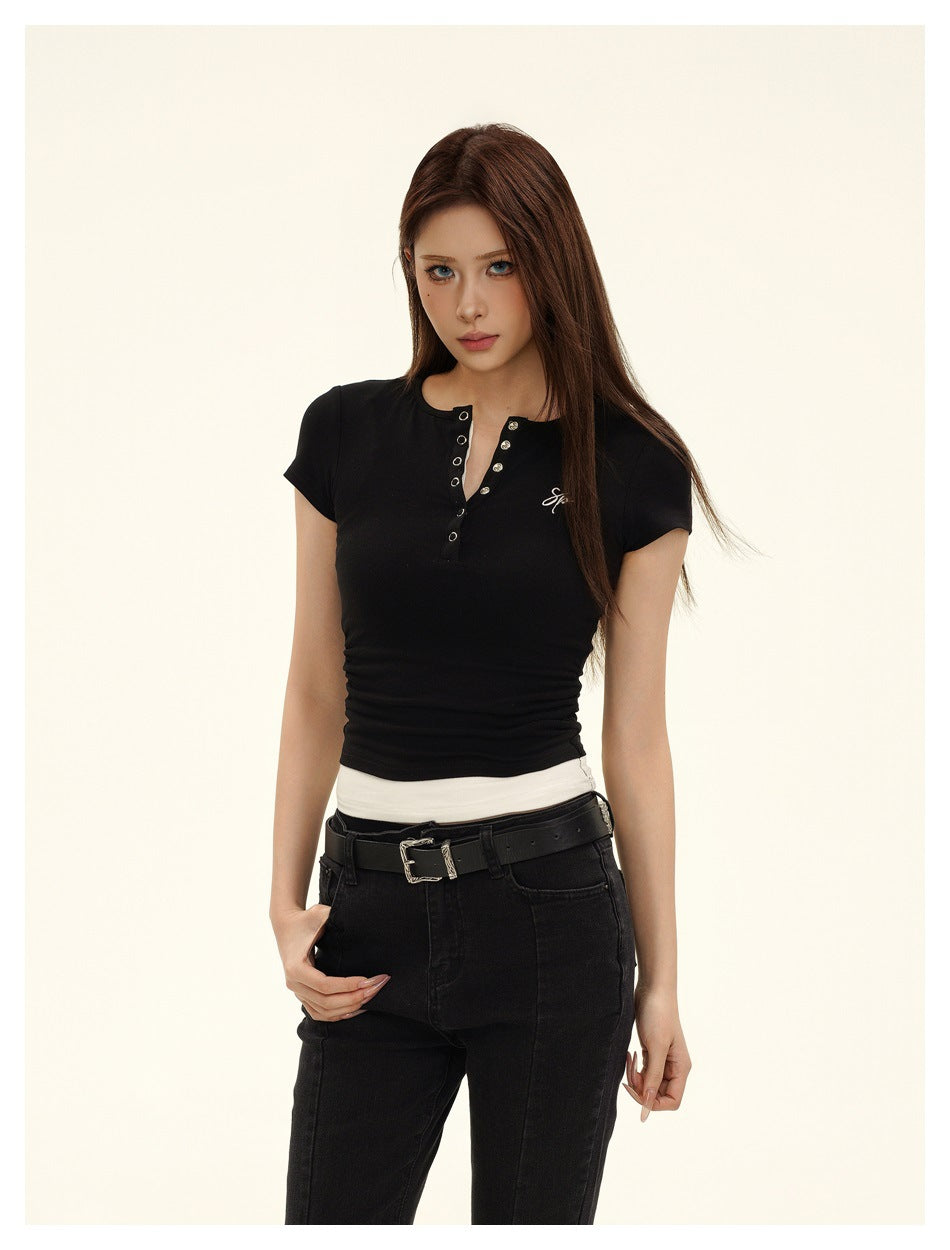 Framed three-quarter view of a model wearing a fitted black short-sleeve top with a metal-eyelet neckline.