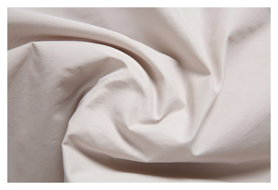 Close-up of softly draped ivory fabric with subtle folds.