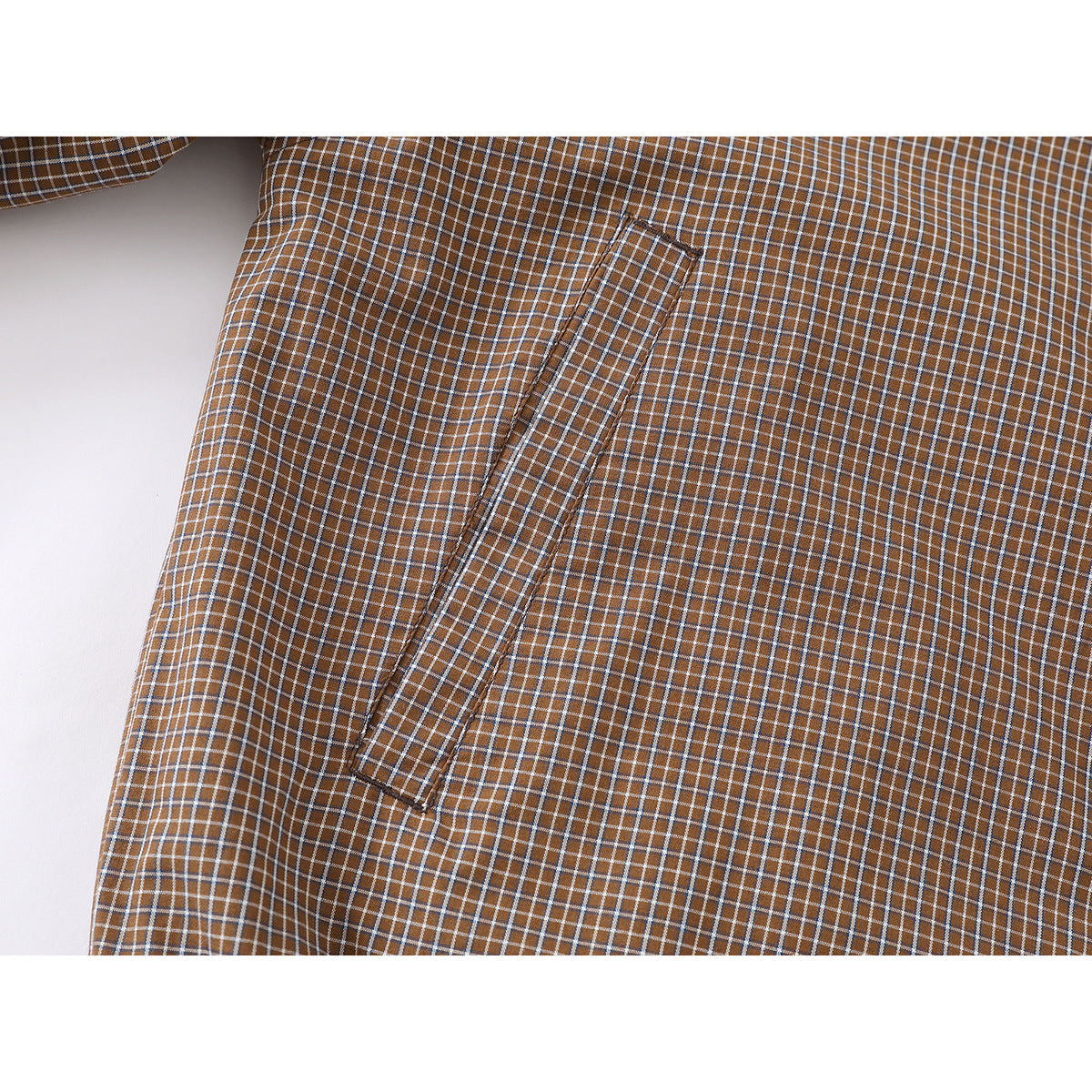 Close-up of brown plaid jacket fabric and a narrow welt pocket.