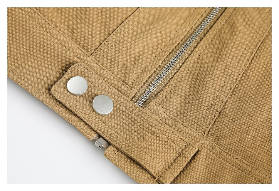 Close-up of a tan jacket cuff or fastening tab with two silver snaps and zipper.