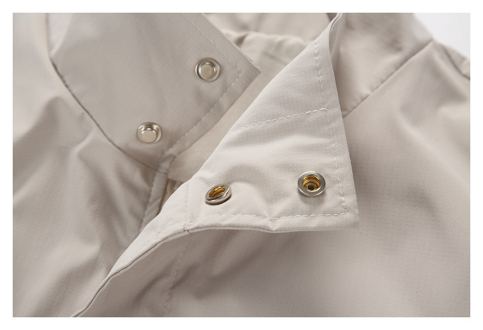 Close-up of metal snap fasteners on the placket of a light beige garment.