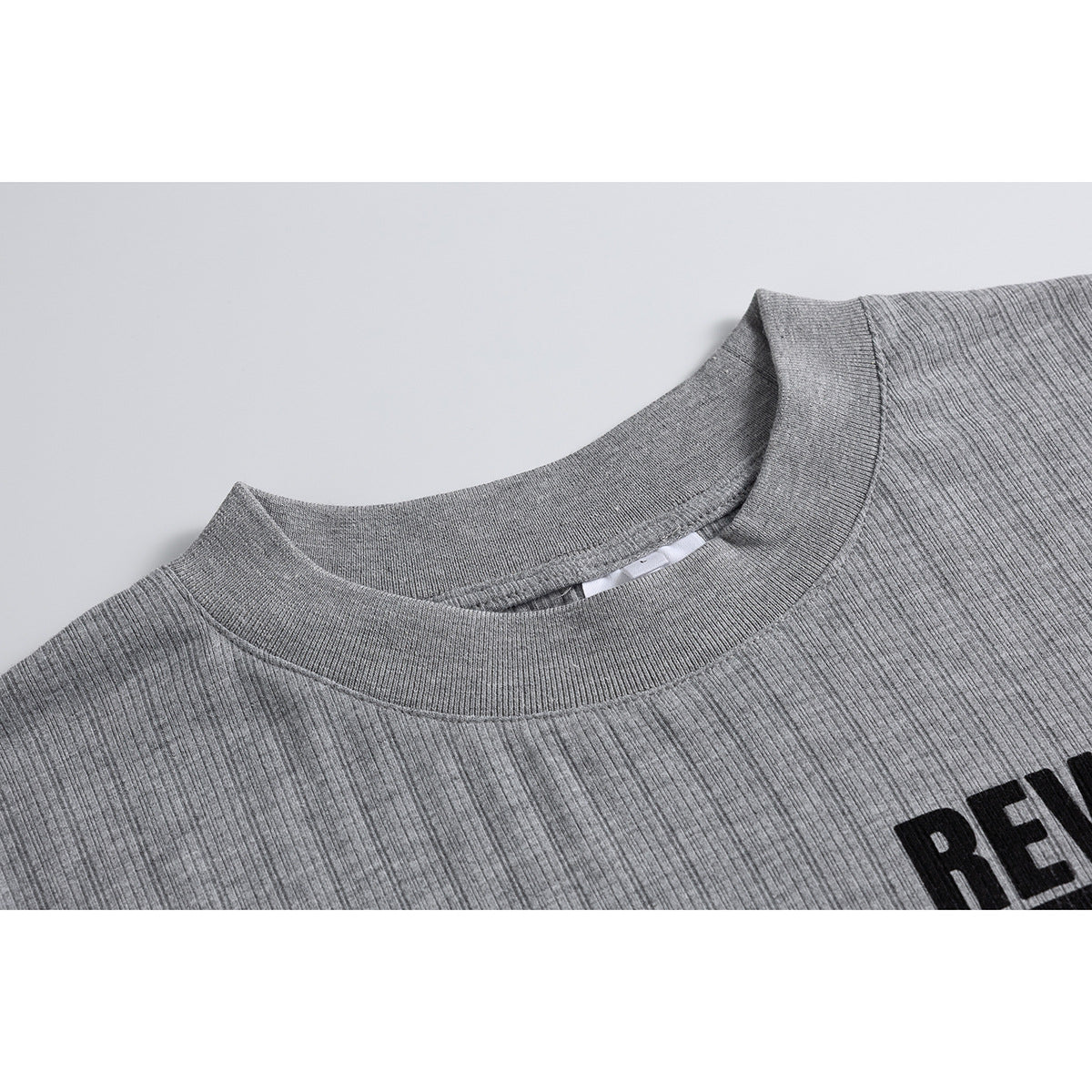 Close-up of the gray ribbed long-sleeve shirt's crew neckline and a small edge of its black graphic.