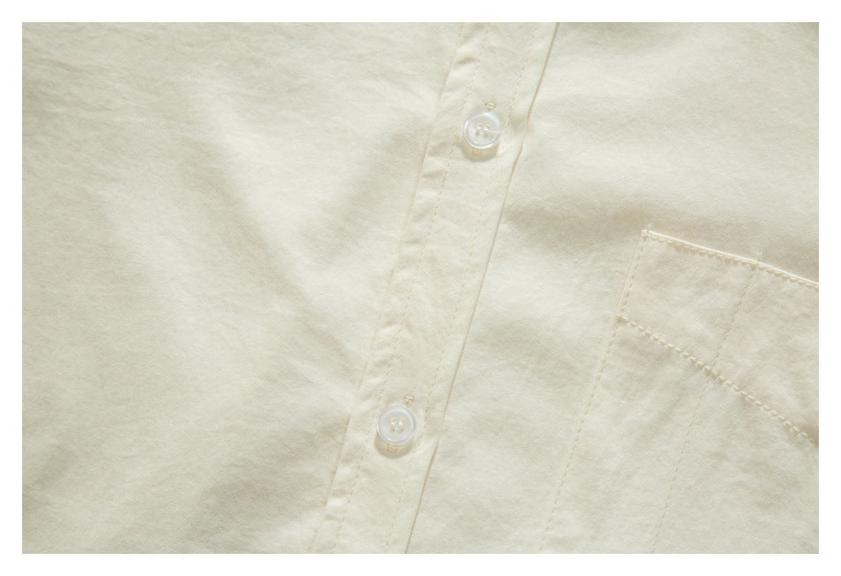 Close-up of the ivory shirt's button placket and stitched chest pocket.
