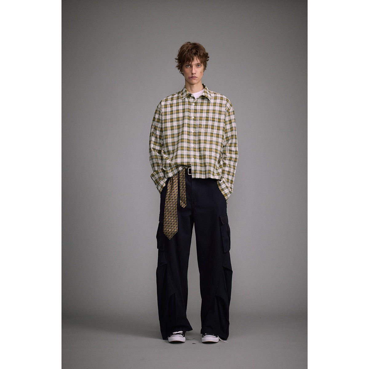 Full-length model wearing an oversized white, green, and mustard plaid button-up shirt with black cargo pants.