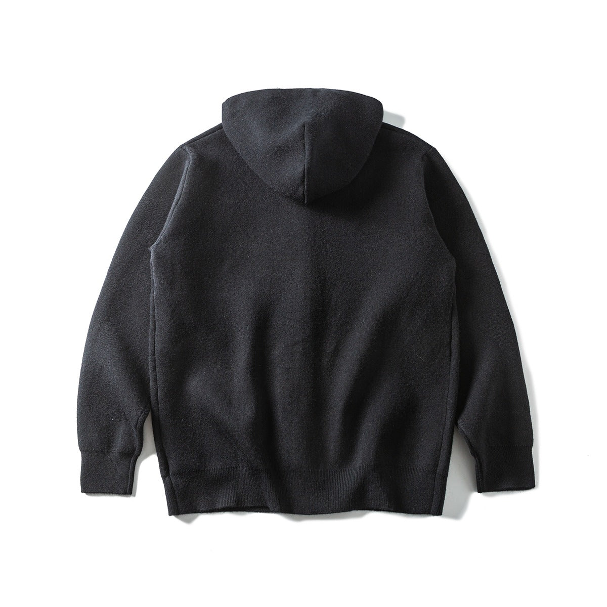 Back view of a dark charcoal hooded knit top laid flat, with long sleeves and ribbed cuffs and hem.
