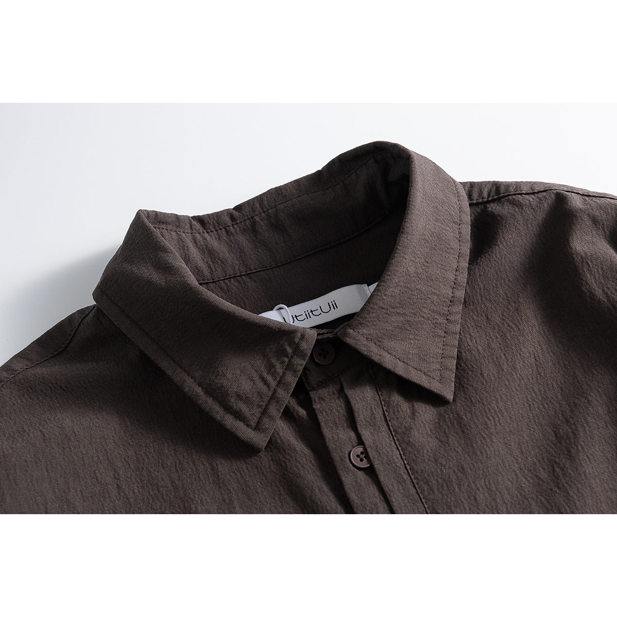 Close-up of a dark brown shirt collar, button placket, and inner neck label.