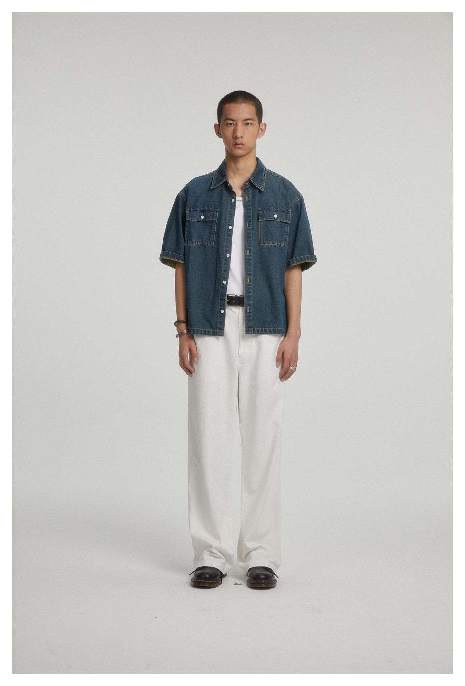 Full-length view of a model in a dark blue denim short-sleeve shirt, white tank top, white wide pants and black shoes
