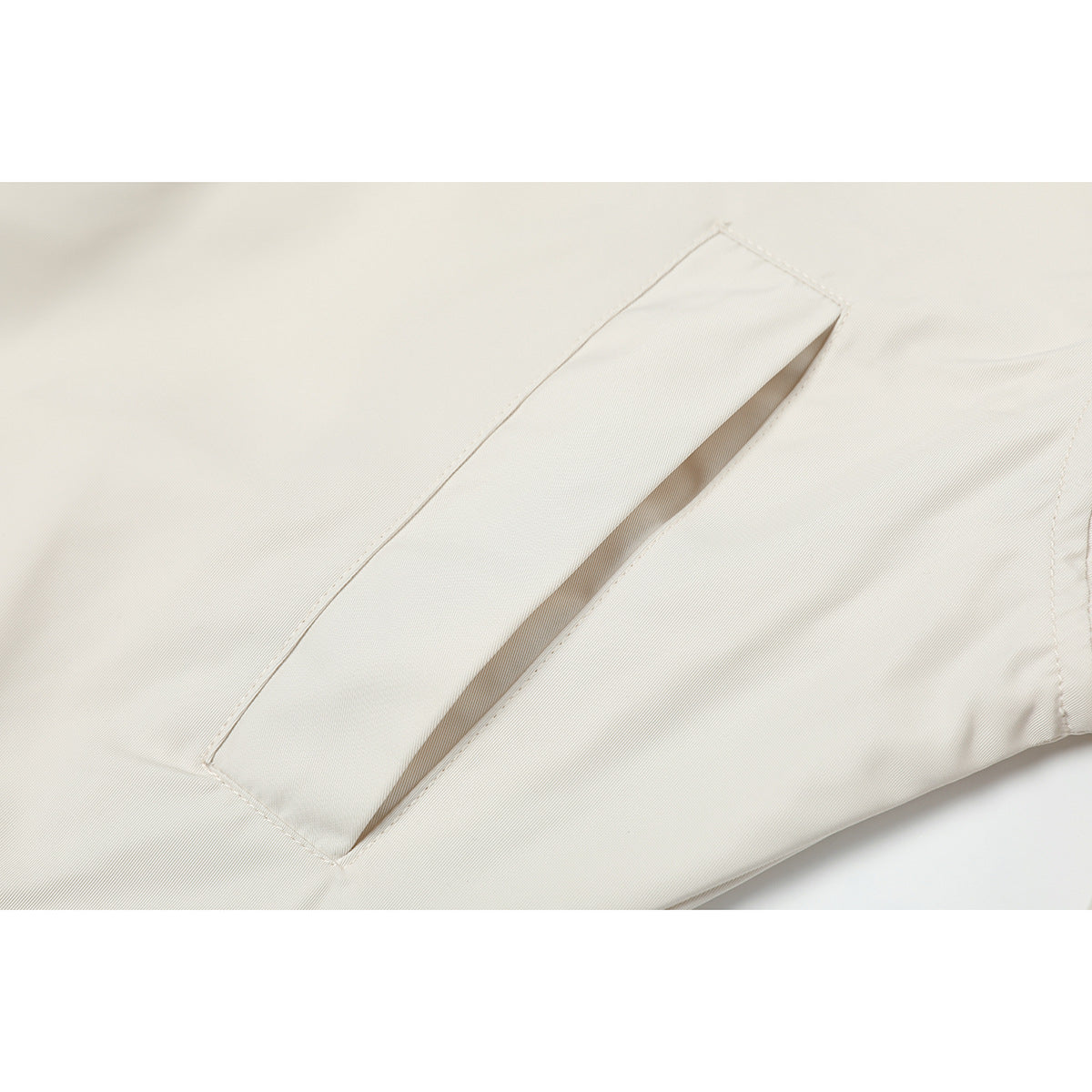 Close-up of a slanted welt pocket on an ivory jacket.