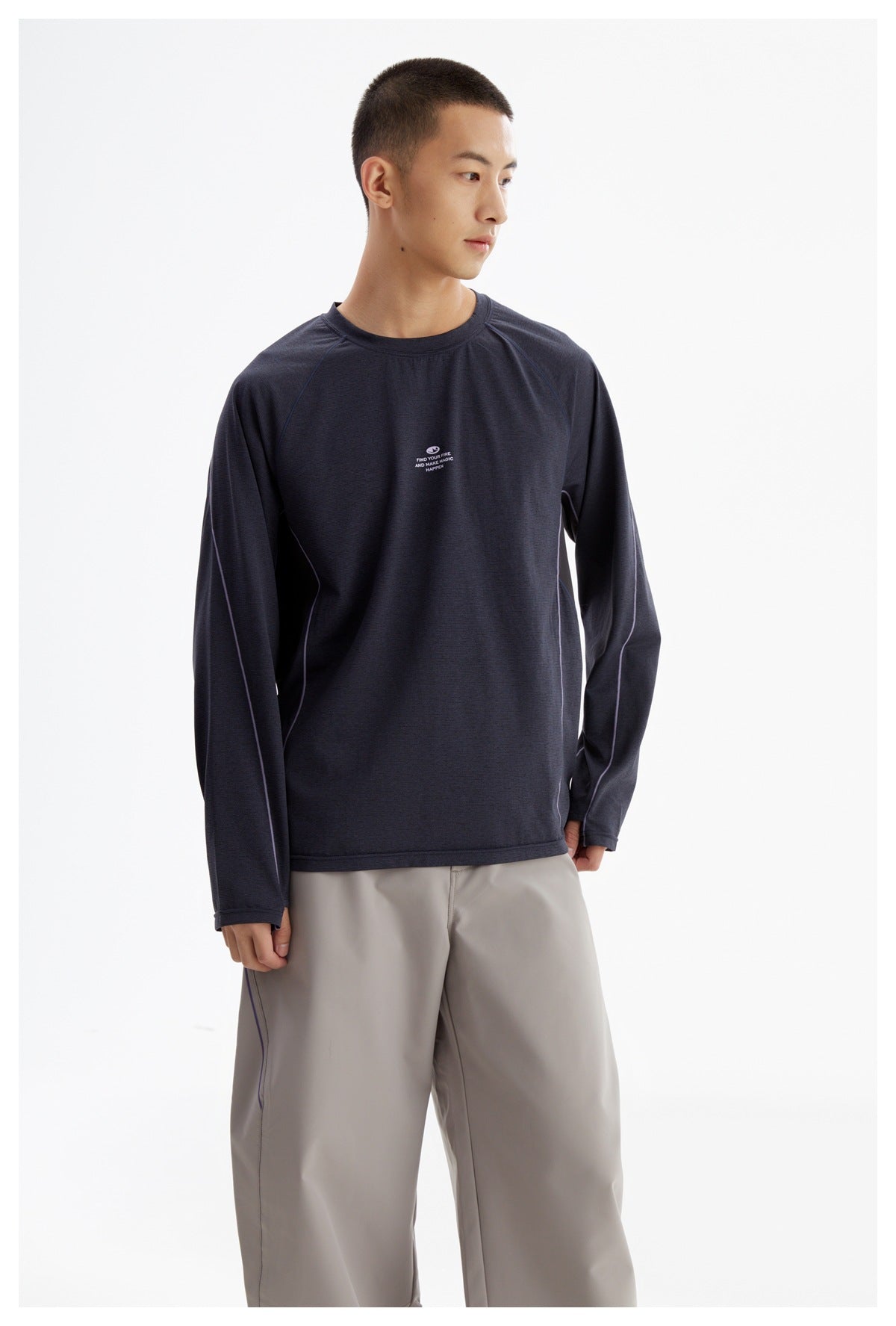 Front view of a model wearing a dark navy long-sleeve crewneck with contrast piping and a small chest print.