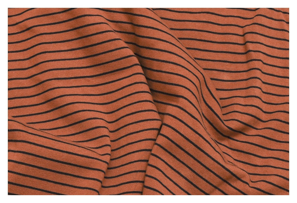 Close-up of rust-brown fabric with thin, dark horizontal stripes, loosely draped.