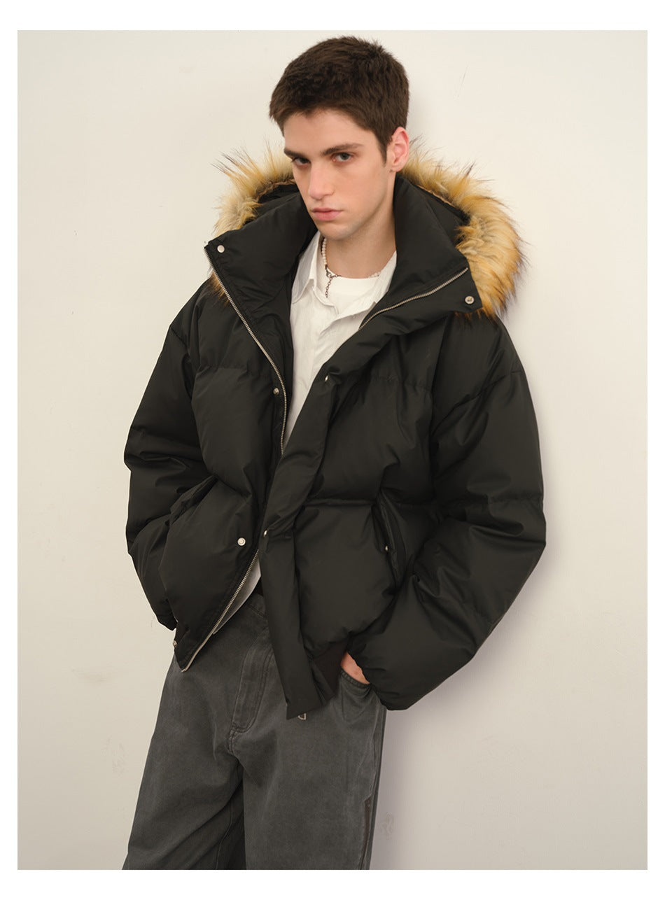 Three-quarter view of a model wearing a black puffer jacket with tan fur-trimmed hood and gray jeans.