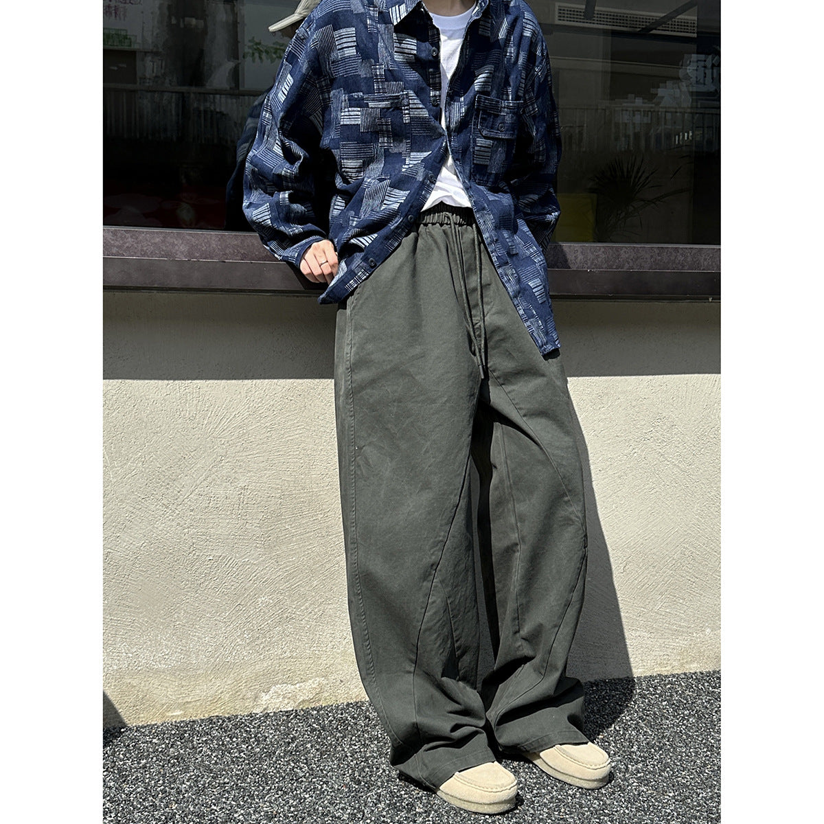 Model wearing oversized charcoal-gray drawstring trousers with a blue geometric-print shirt.
