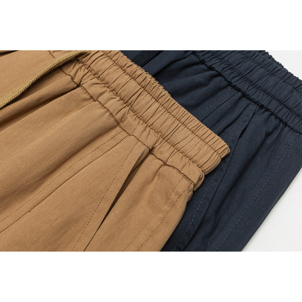 Close-up of tan and dark navy shorts showing elastic waistbands and stitched fabric panels.